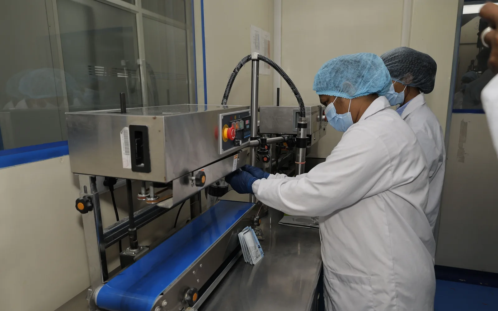 Two operators running the sachet sealer on the packing line